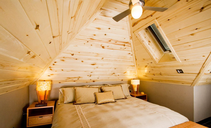 Отделка стен и потолка мансарды деревом позволяет сделать спальню уютной, натуральной и экологичной